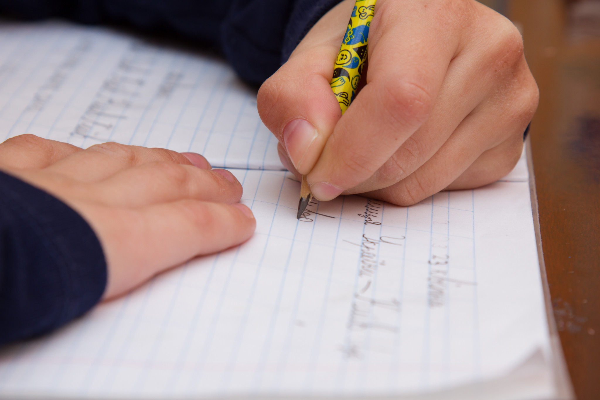 Barn skriver sina läxor med blyertspenna mot pappersblock.