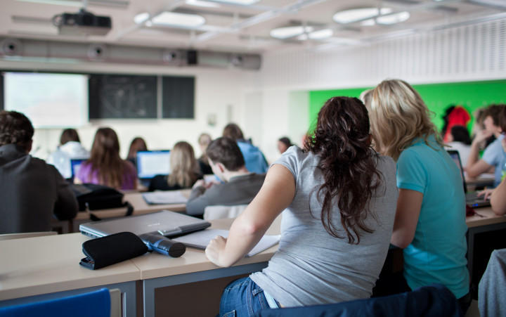 Elever i klassrum. Två unga kvinnor i fokus.