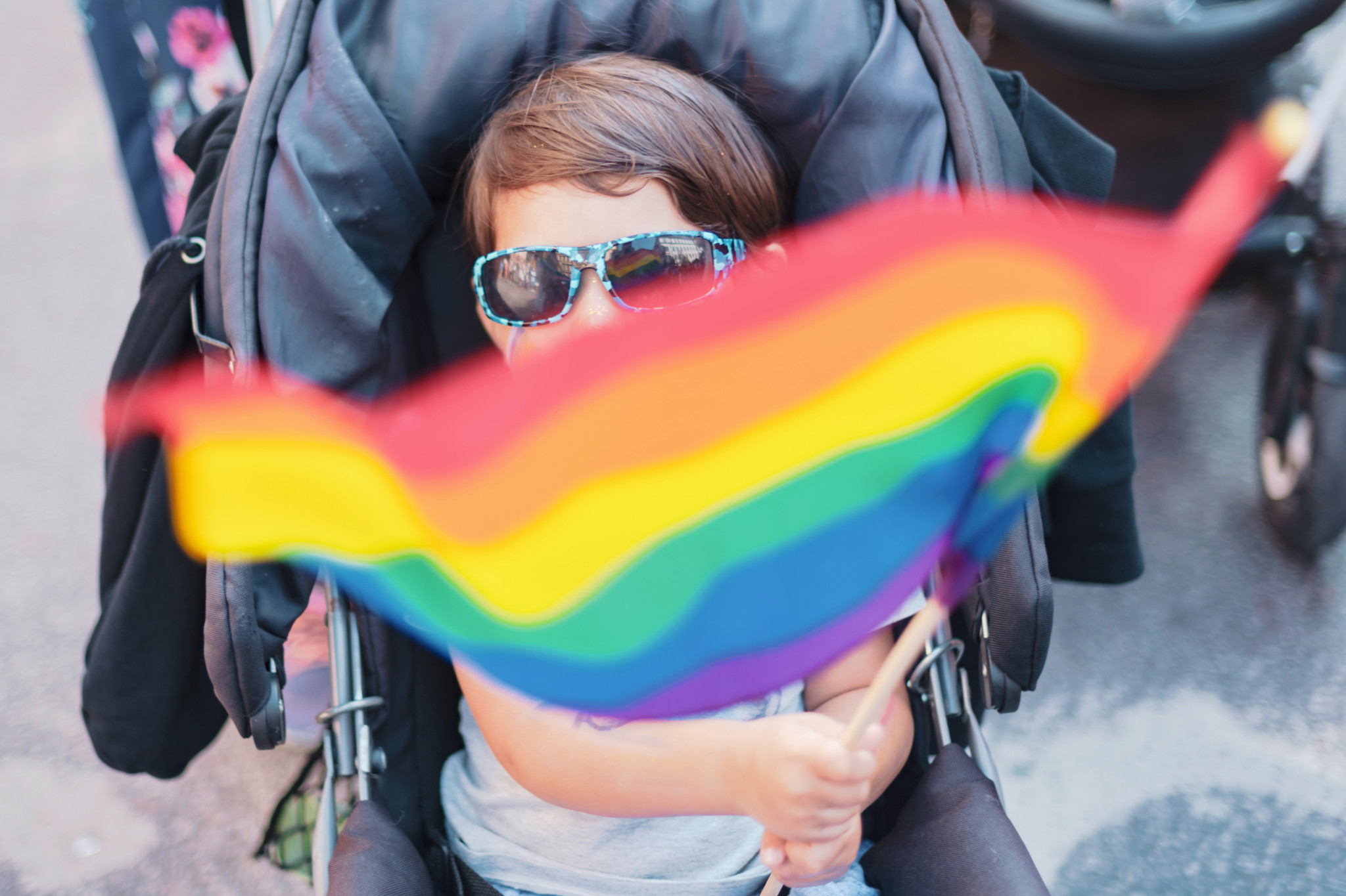 Barn i barnvagn hållandes prideflagga