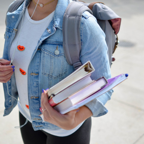 Student hållandes i kurslitteratur och anteckningsblock