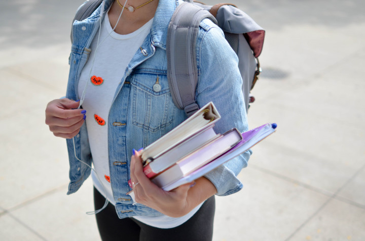 Student hållandes i kurslitteratur och anteckningsblock