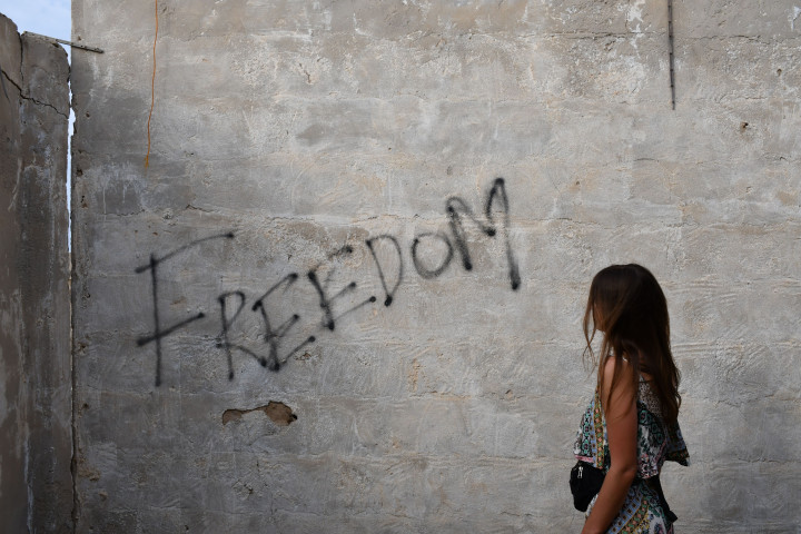 Ung kvinna med blicken mot graffitikonst med motivet "Freedom"
