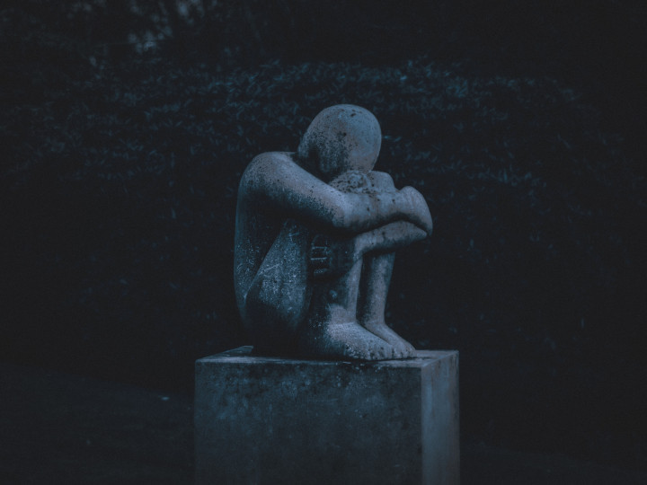 Staty av hopkurad person som symboliserar psykisk ohälsa. Mörk siluett.