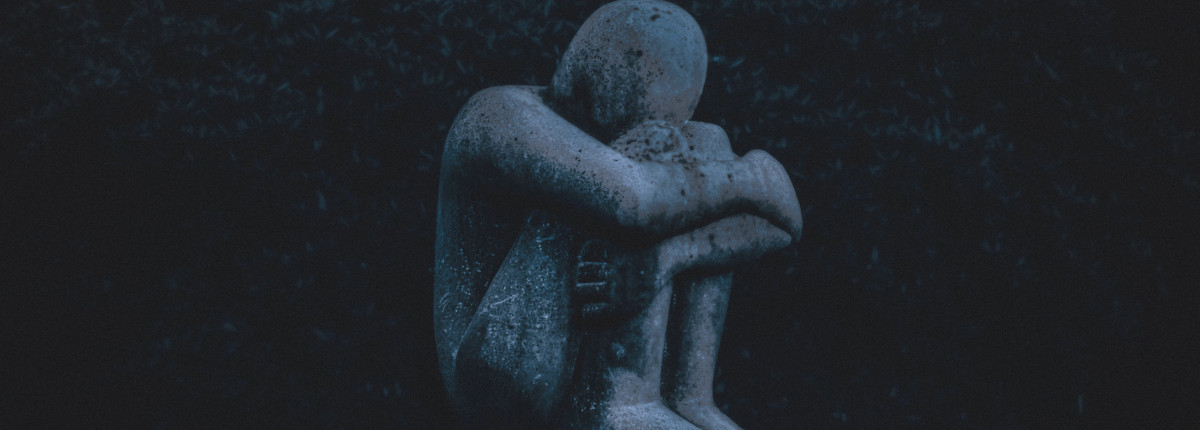 Staty av hopkurad person som symboliserar psykisk ohälsa. Mörk siluett.