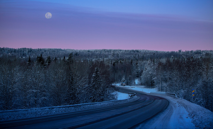 Snötäckt landsväg i solnedgång.